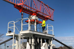 Two people working on radio attachment on tower