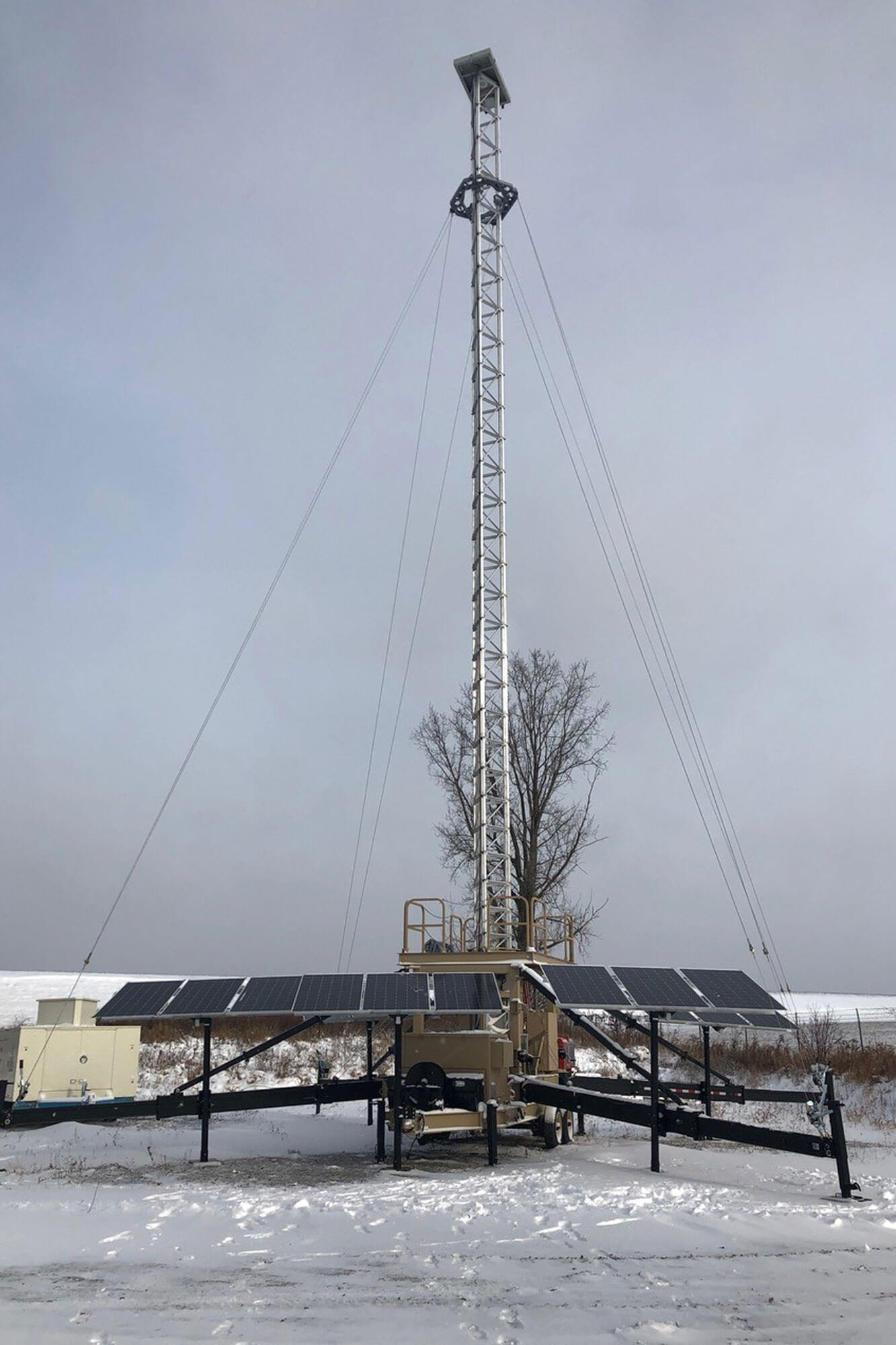 Tower extended with outriggers, solar panels.